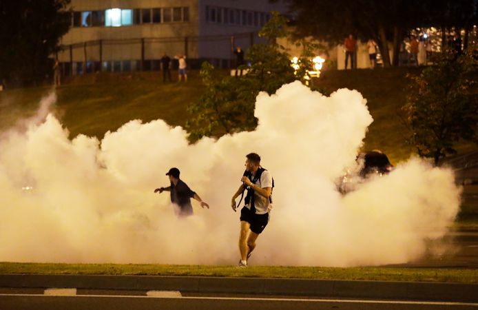 Demonstranten rennen weg nadat de politie verdovingsgranaten afvuurt in Minsk.