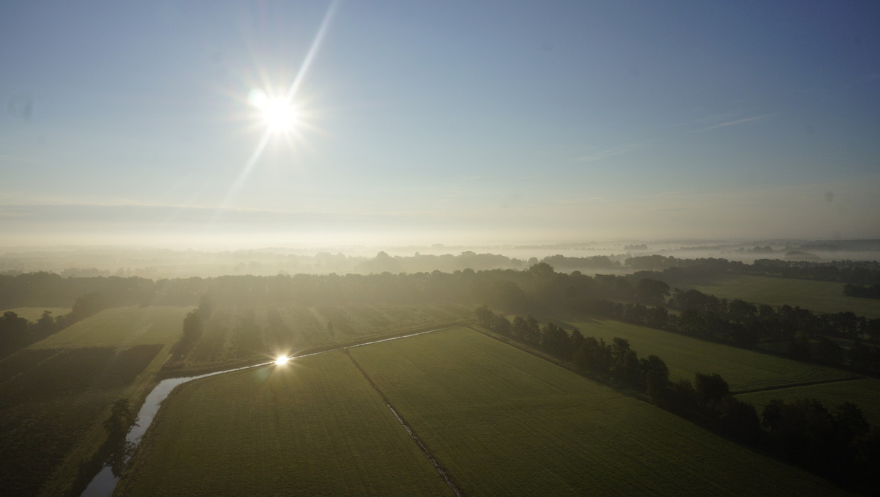 Luchtfoto van een opkomende zon in de mist boven Friese weiden. Beeld anp