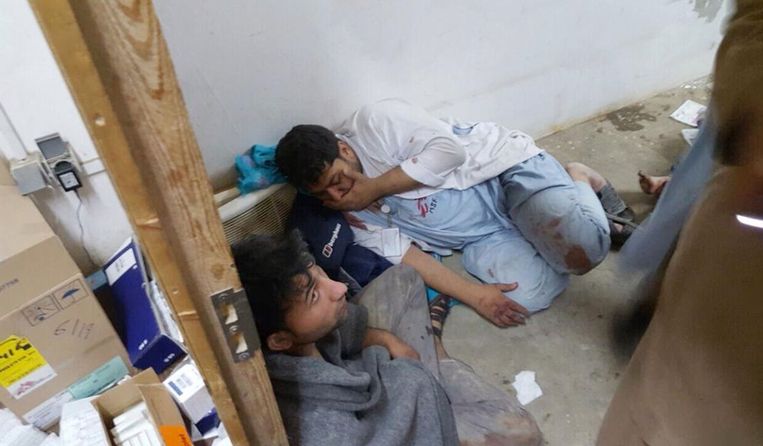 Medewerkers van het ziekenhuis zoeken dekking na het bombardement. Beeld AP