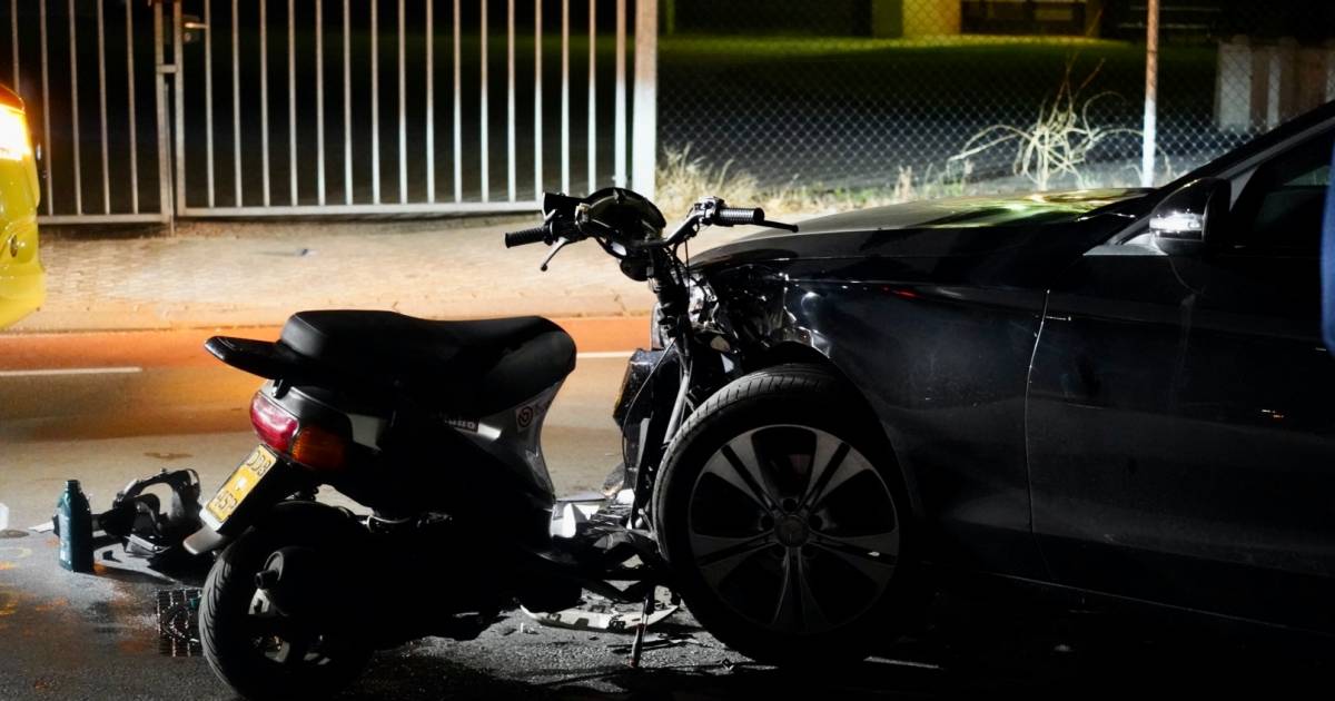 Scooter zit na aanrijding vast bij voorwiel van auto.