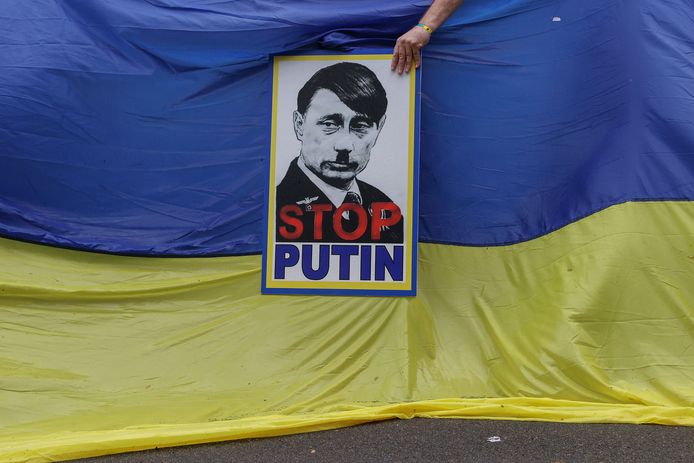 Een protestbord voor de Oekraïense vlag toont de Russische president Vladimir Poetin afgebeeld als Adolf Hitler.