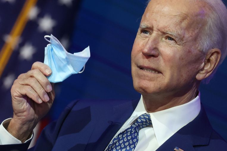 Joe Biden houdt een mondkapje vast tijdens de presentatie van zijn plannen om het coronavirus in te dammen. Beeld REUTERS