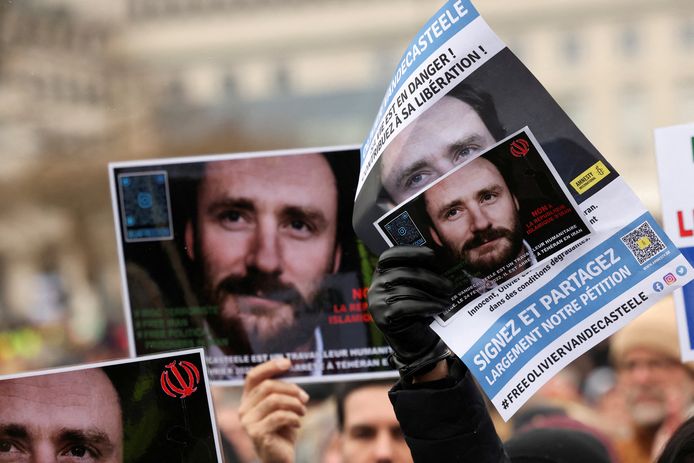 Mensen houden affiches omhoog met daarop het gezicht van Olivier Vandecasteele die al een jaar in een Iraanse cel zit voor zogezegde spionage.