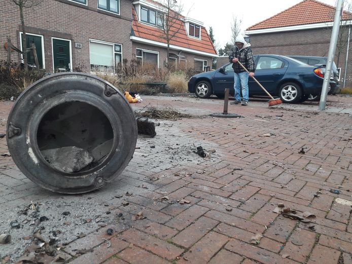 Een buurman veegt de plek schoon, waar Henk Kempers uit Enschede vlak na middernacht als gevolg van een vuurwerkexplosie overleed.