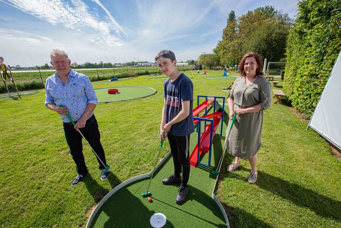 Carine Verbruggen (55) en Gilbert Verhaegen (63) met zoon Milan op het minigolfterrein in hun tuin.