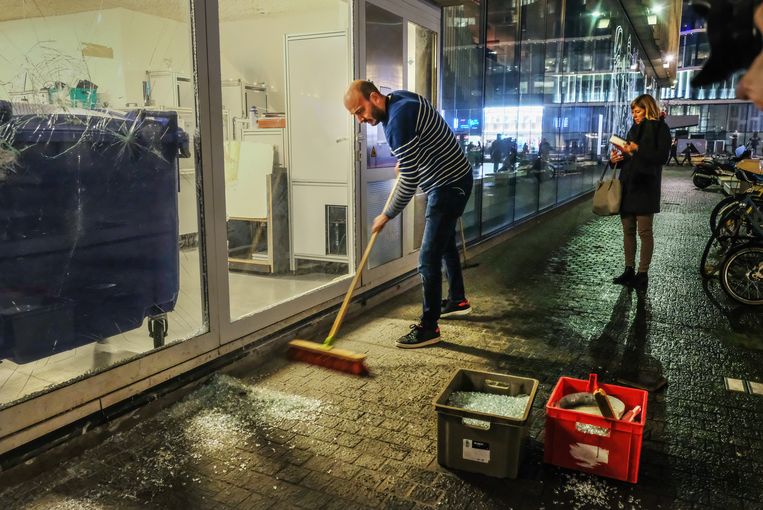 Een man veegt de glasscherven bij elkaar na de rellen op het Muntplein in Brussel. Beeld Tim Dirven