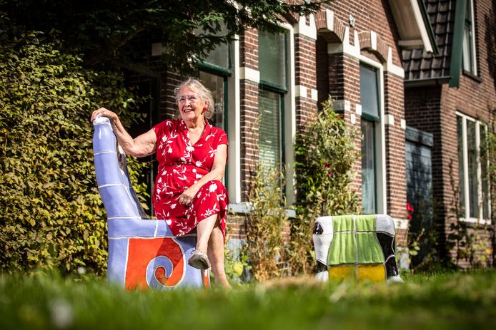 Guusje Beverdam, zittend op de stoel voor haar huis die zo kenmerkend is voor haar werk.