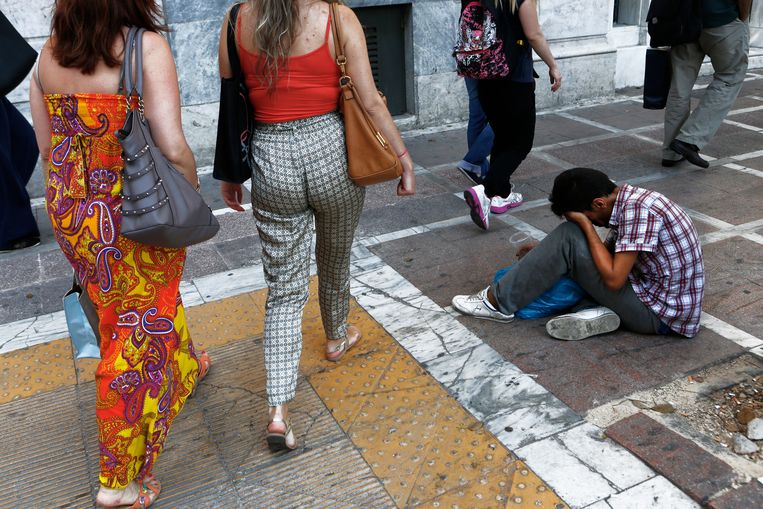 Zomer 2015: een bedelende man zit op straat voor het gebouw van de Griekse nationale bank in Athene. Door een combinatie van financieel wanbeleid en de kredietcrisis waren de Grieken vanaf 2010 in een enorme schuldencrisis beland. Beeld AP