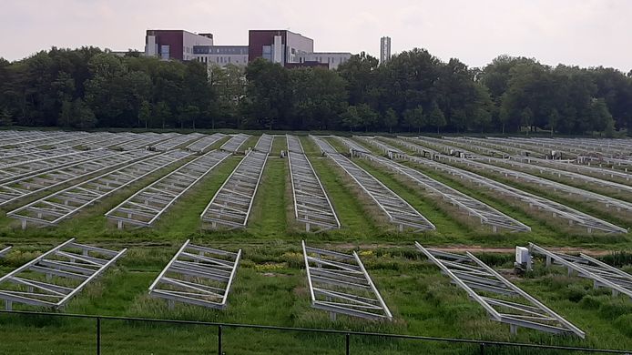 Het zonneveld in aanbouw met op de achtergrond ziekenhuis Meander Medisch Centrum.