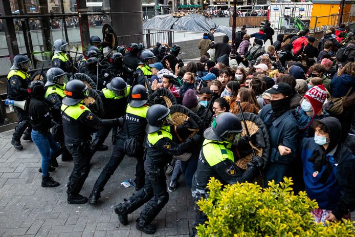 Politieagenten proberen demonstranten op het Rokin in Amsterdam tegen te houden.