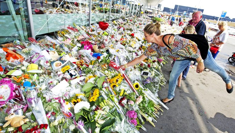 Een vrouw legt op Schiphol bloemen neer ter nagedachtenis van de slachtoffers van de neergehaalde MH17. Beeld GETTY