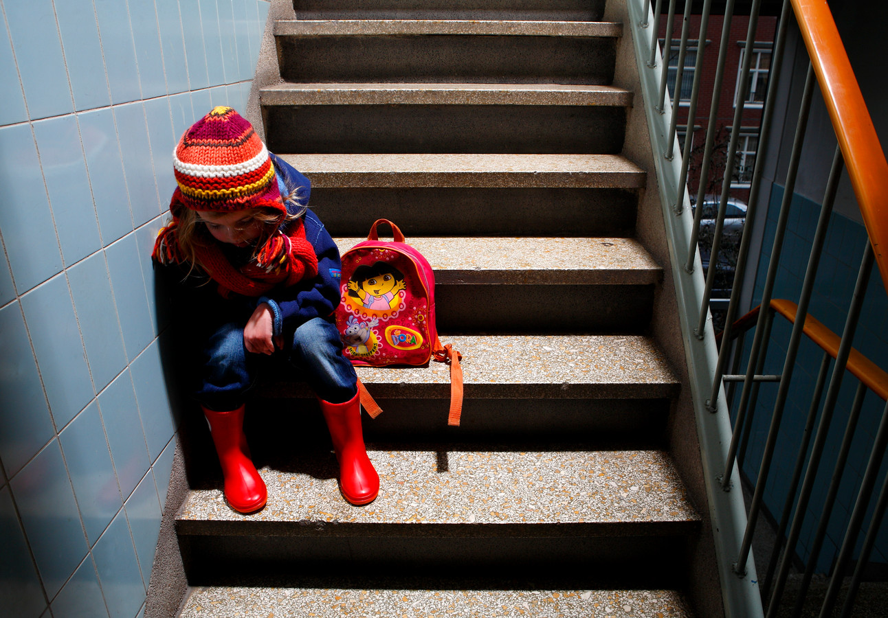 Een meisje zit op de trap in haar basisschool.
