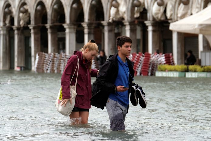 Toeristen waden door het ondergelopen San Marco-plein.