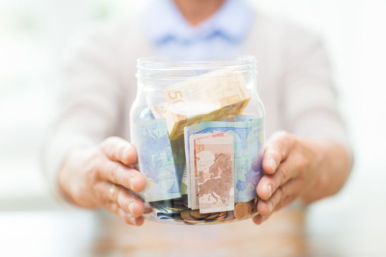 savings, money, annuity insurance, retirement and people concept - close up of senior woman hands holding money in glass jar Beeld Thinkstock