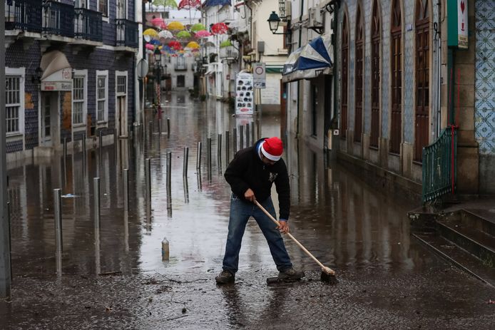 Een man kuist modder op na overstromingen in Agueda, Portugal.