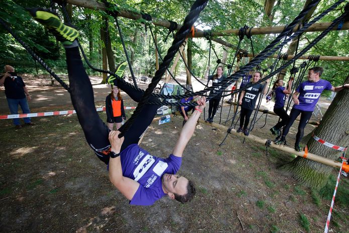 Deelnemers aan de SurviFELrun bedwingen een hindernis in Park Brakkenstein.