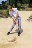 Melvin Muller tijdens een bunkershot op de golfbaan in Bakel die hij op z'n duimpje kent.