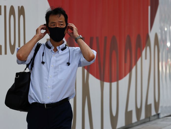 Un homme portant un masque passe devant un panneau des Jeux olympiques de Tokyo 2020 à Tokyo, au Japon, le 28 juillet 2021.