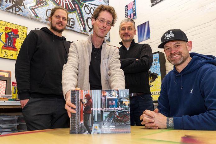 Bossche fotograaf Ben Nienhuis met zijn fotoboek met foto’s van de kunstenaars van Kings of Colors die na de avondklokrellen de panelen van de getroffen winkels kleur gaven. V.l.n.r.: Frank Willems, Ben Nienhuis, Stefan van Ham en Jan Henk van Ieperen.