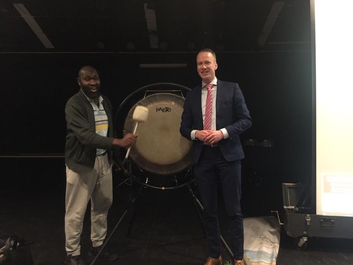 Musa Mawanda en wethouder Cees van den Bos openen de Vacaturemarkt Renesse met een klap op de gong. Mawanda doorliep met succes een integratieproject en werkt nu bij een groot installatiebedrijf op het eiland