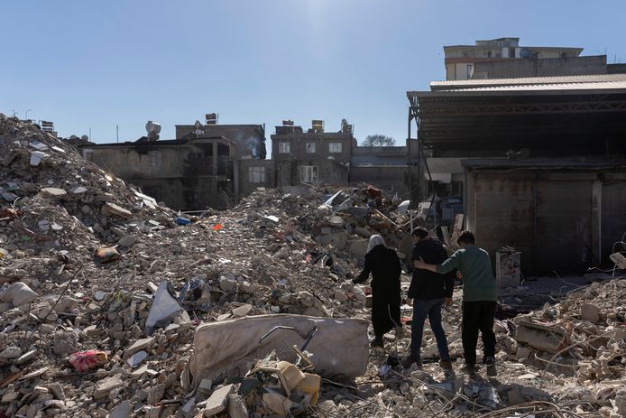 Een familie loopt door de puinhopen van hun voormalige huis in het rampgebied van de aardbeving in Turkije.