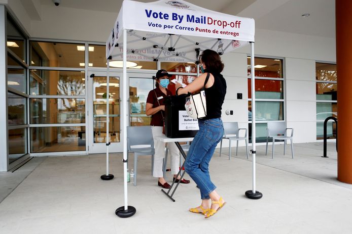 Een vrouw komt haar stembiljet dat ze per post heeft gekregen afleveren in East Tampa, Florida.
