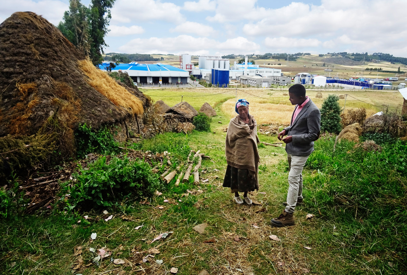 Manager bij de Habesha-bierbrouwerij in Ethiopië Biruk Assegid (l) in gesprek met een van de omwonenden,  Atsede Feke. Op de achtergrond de brouwerij.