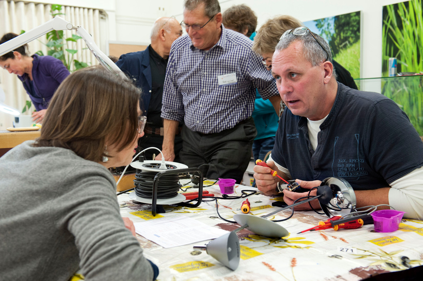 Een van de vrijwilligers van Repair Cafe in 2015 tijdens de reparatie van de leeslamp van een Nieuwegeinse dame.
