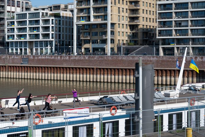 Nijmegen: gymnastiek door Oekraïense vluchtelingen op het dek van cruiseschip Traviata in de Waalhaven tegen een decor van balkons met blauw-gele vlaggen aan de Handelskade