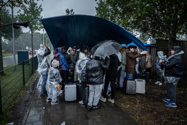 Vluchtelingen staan buiten in de regen bij het aanmeldcentrum voor asielzoekers in Ter Apel.  Beeld Kees van de Veen