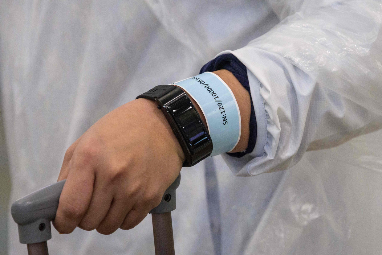 Reizigers die in Hongkong arriveren, krijgen een quarantaine-armband met een locatietracker. Beeld AFP
