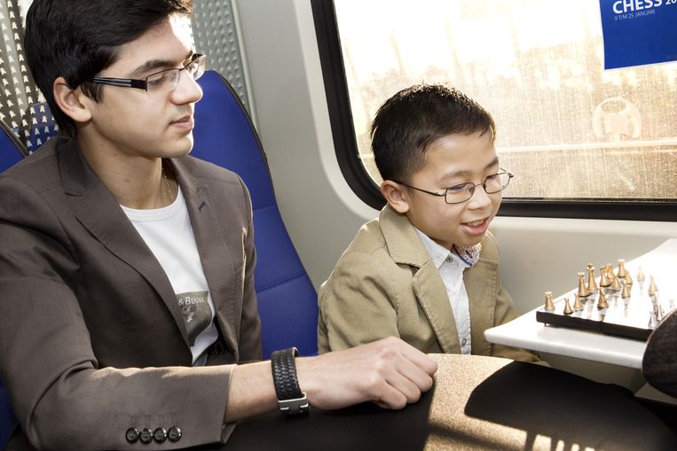 Anish Giri helpt een jong talent bij het schaken tegen een medereiziger in de trein. Beeld Io Cooman