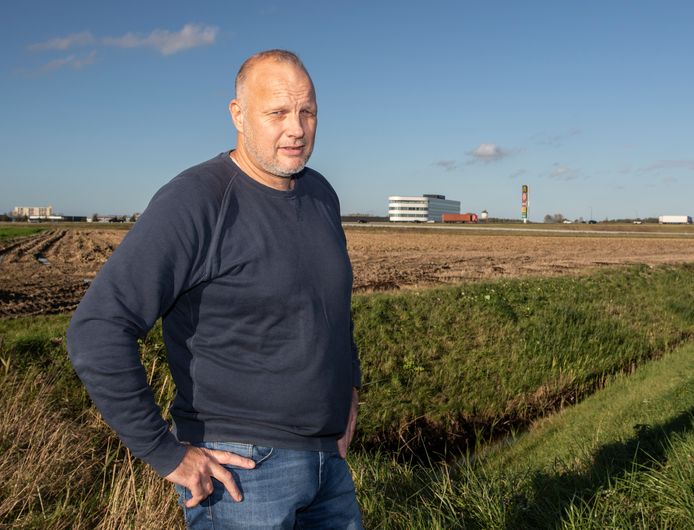 Jan-Kees de Meester met op de achtergrond het kantoorpand van Roompot en de hoge zuil van de fastfoodboulevard bij Goes.