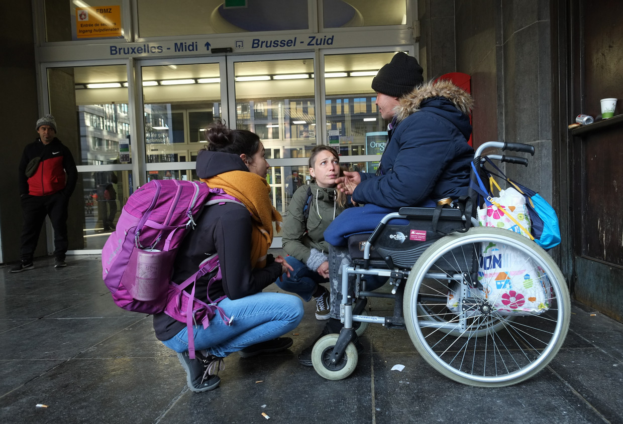 Straatwerkers Sarah and Elisabeth ontfermen zich over een dakloze in Brussel. Beeld BELGA