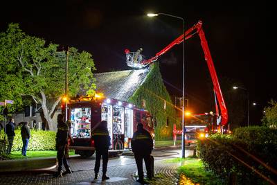 Schade aan woning bij schoorsteenbrand in Den Hout, brandweer blust vuur met hoogwerker