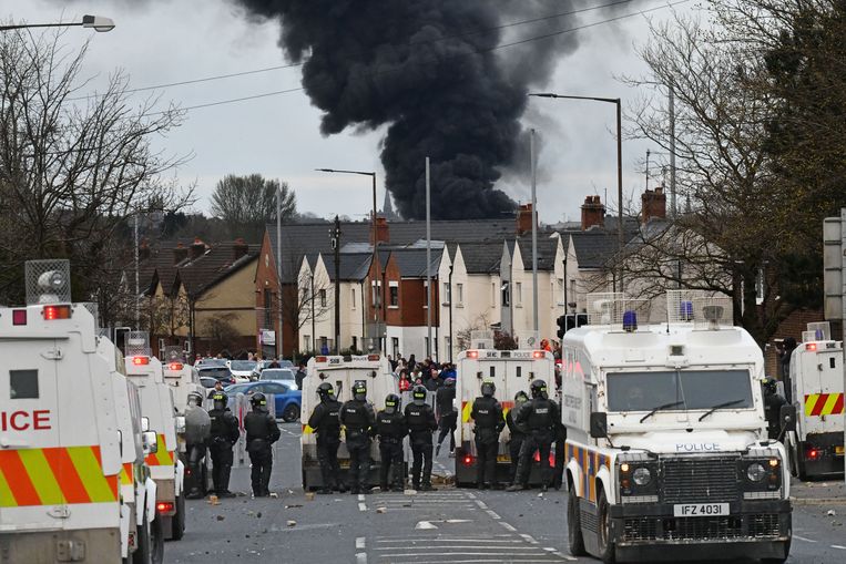 Politie raakt slaags met demonstranten in West-Belfast, met op de achtergrond de rook van een uitbrandende bus. Beeld Reporters / Splash