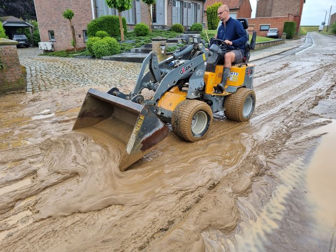 Een buurtbewoner probeert de modderstroom in Landen onder controle te krijgen.