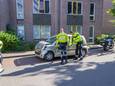 Politieagenten bij de gedeukte auto in de Meeuwenlaan, nadat die was doorgereden na een botsing.