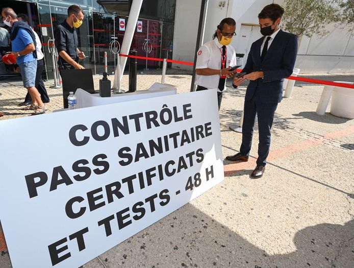 Le secrétaire d'État français et porte-parole du gouvernement, Gabriel Attal (R), montre son "pass sanitaire" à un fonctionnaire lors de sa visite au cinéma Gaumont Multiplex Odyséum à Montpellier, dans le sud de la France, le 29 juillet 2021.
