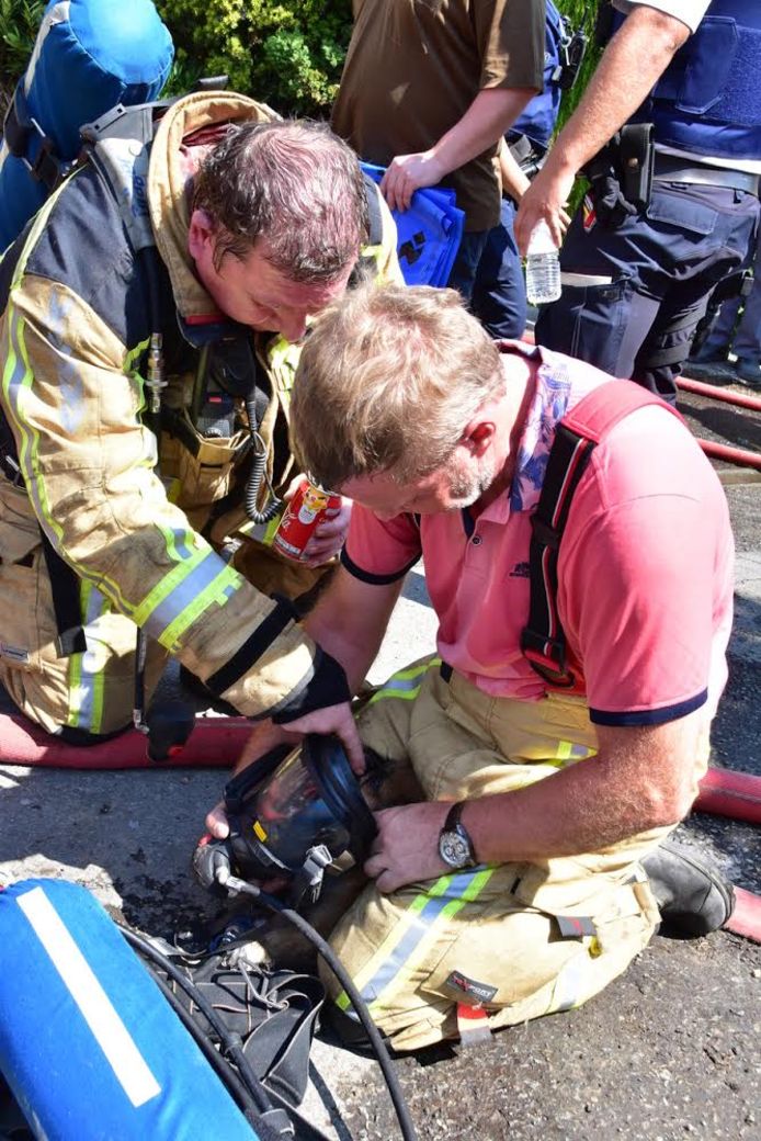 Brandweermannen beademen een hond die uit het vuur gered werd.