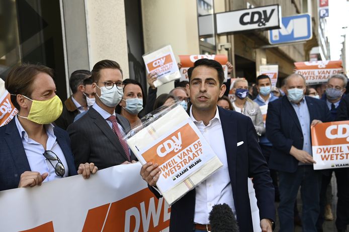 Partijvoorzitter Tom Van Grieken houdt een dweil vast.  Prominente VB'ers trokken naar het CD&V-partijhoofdkwartier aan de Brusselse Wetstraat.