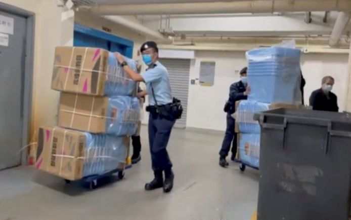 Gli agenti sequestrano scatole piene di prove durante una perquisizione in redazione.