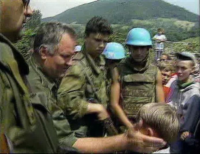 Lichtbewapende Nederlandse VN-blauwhelmen stonden machteloos toen de troepen van Ratko Mladic (links) Srebrenica onder de voet liepen. Mladic liet eerst nog snoep uitdelen aan kinderen, toen de Servische cameraploeg vetrok, werden vrouwen en kinderen gescheiden van mannen. Bij moordpartijen door de Bosnische-Servische troepen zijn in de dagen erna naar schatting 8.000 moslimmannen -en jongens om het leven gekomen.