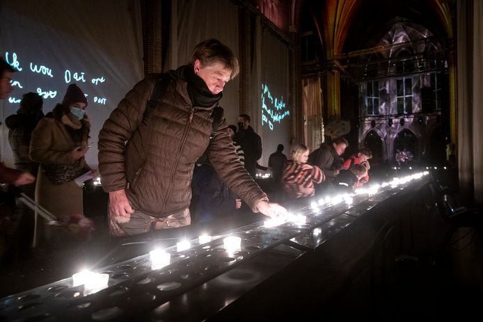 Mensen steken een kaarsje aan in De Wensfabriek in de Paterskerk in Eindhoven tijdens Glow.