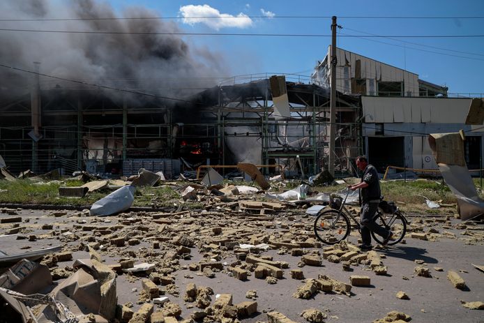 Een inwoner wandelt met een fiets langs een industrieel pand in Bakhmut (Donetskregio), dat werd beschoten door Russische troepen. (27/05/2022)