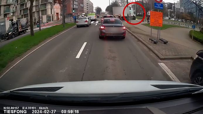 De fietser (in het rood omcirkeld) wordt meegesleurd door de vrachtwagen.