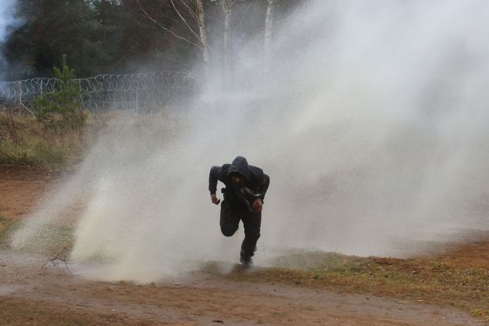 Een man probeert weg te lopen van het waterkanon.