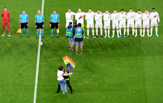 A protestor is apprehended by security after he ran onto the field holding a Rainbow Flag and stood in front of the Hungarian team during Hungary's national anthem before the Euro 2020 soccer championship group F match between Germany and Hungary at the football arena stadium in Munich, Germany, Wednesday, June 23, 2021. (Matthias Hangst/Pool Photo via AP)