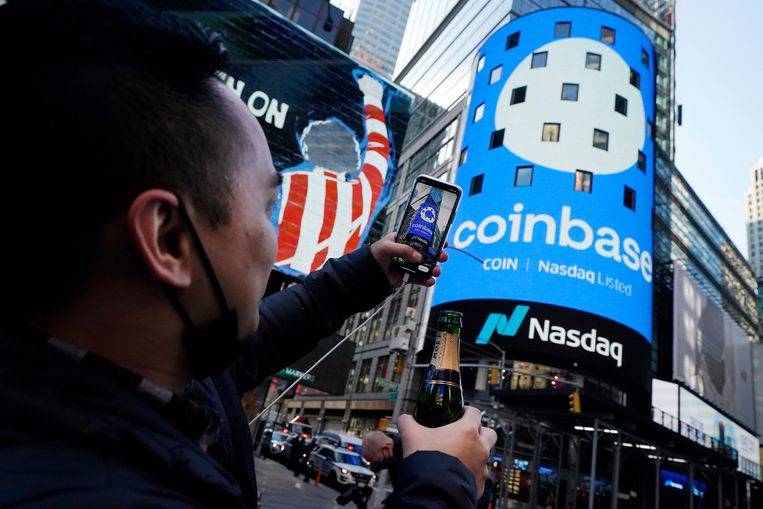 Een werknemer van Coinbase fotografeert de pui van technologiebeurs Nasdaq op Times Square in New York, waarop de naam van het bedrijf wordt geprojecteerd. Beeld AP