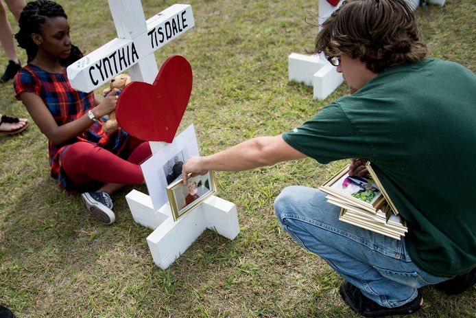 Een leerling zet een foto bij het herdenkingskruisje voor Cynthia.
